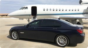 A VIP black BMW parked in front of a private jet.