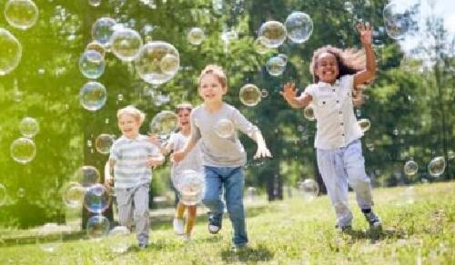 Children playing with soap bubbles in a park, filled with joy and forgiveness.