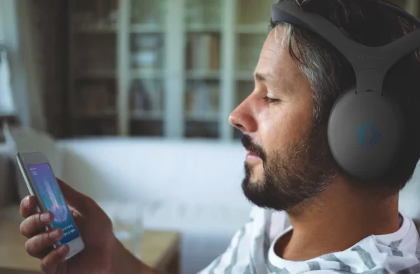 A man engaged in brain training while wearing the Sens.ai Meditation & Brain Training Headset and looking at his phone.